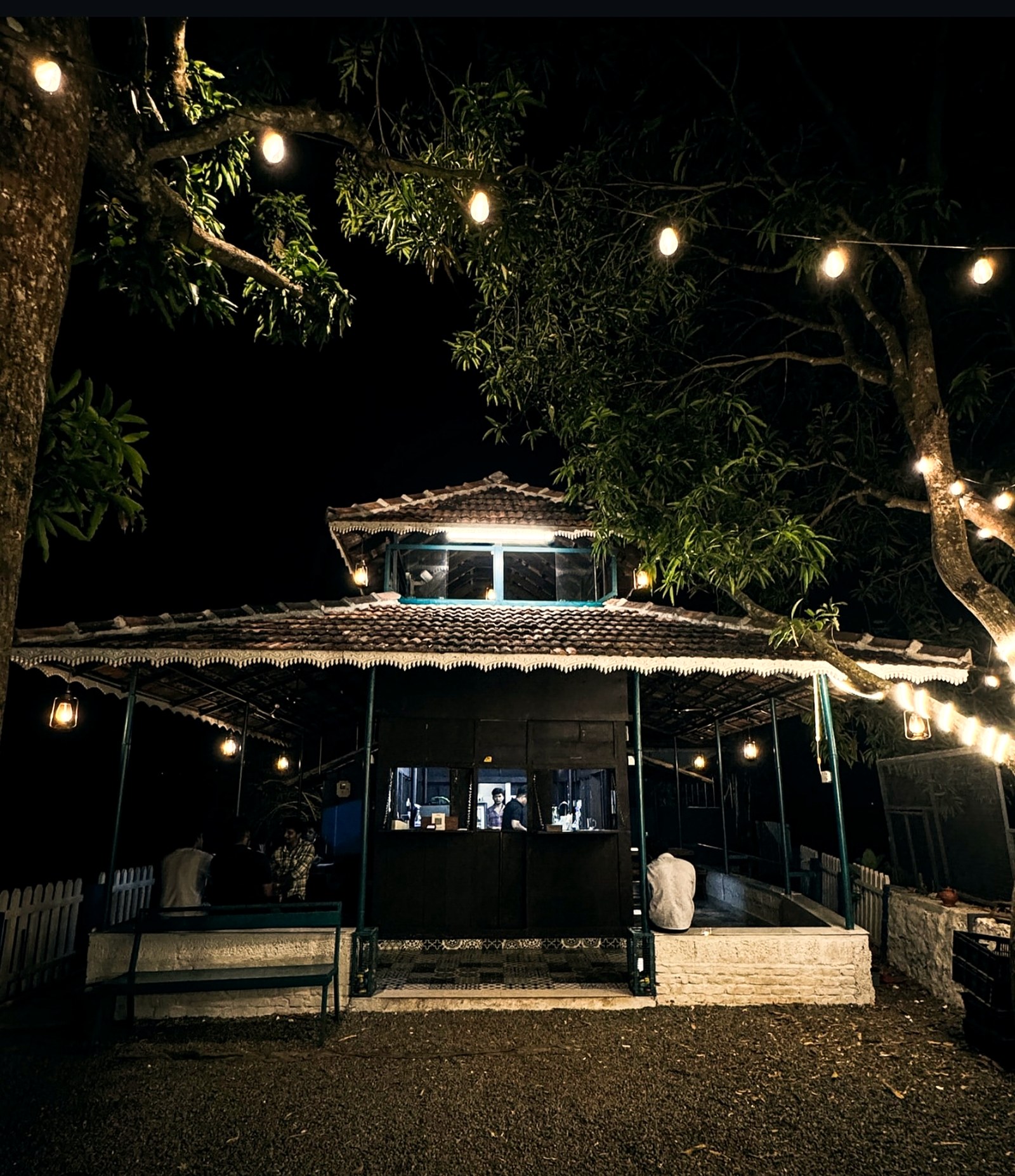 MAN.KO Resto Cafe at night, string lights under the mango trees